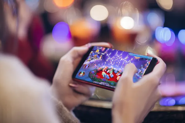 A young woman relaxing with her phone while dynamic casino elements float around her, illustrating the smooth mobile experience offered by the KKBDT app.