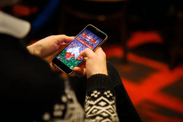 A man focused on his laptop with live stats in the background, highlighting the dedicated sports and gaming features of the KKBDT mobile app.
