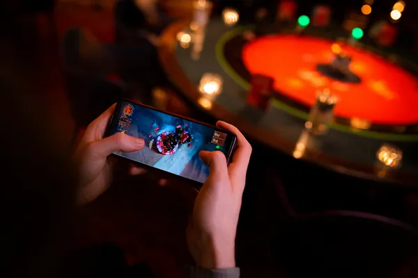 A player using their smartphone during a festive local event, representing KKBDT’s fully mobile-friendly casino.